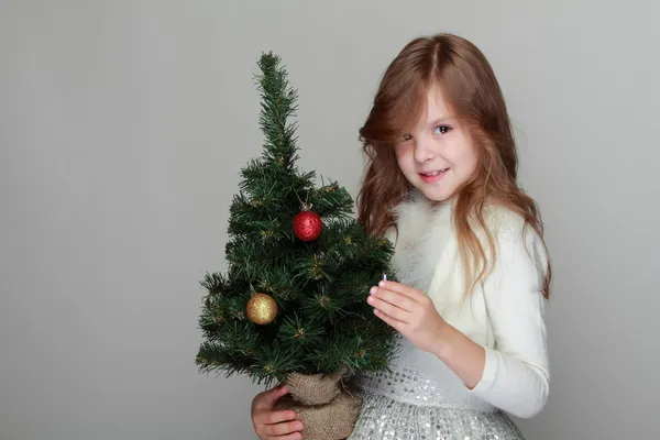 Menina segurando uma pequena árvore de Natal — Fotografia de Stock