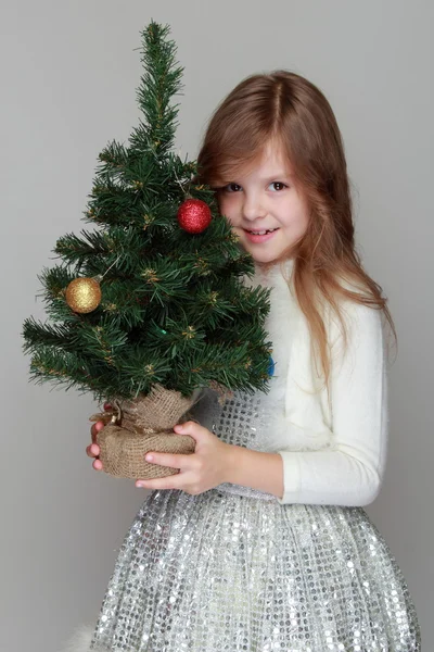 Flicka som håller en liten julgran — Stockfoto