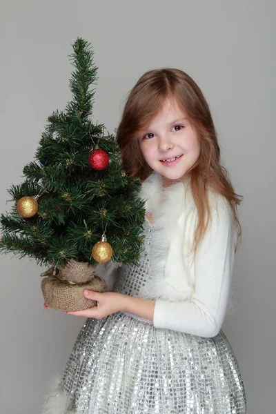 Chica sosteniendo un pequeño árbol de Navidad — Foto de Stock