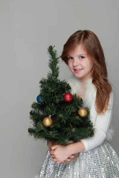 Chica sosteniendo un pequeño árbol de Navidad —  Fotos de Stock