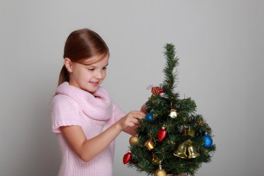 çocuğun yanında dekore edilmiş bir Noel ağacı