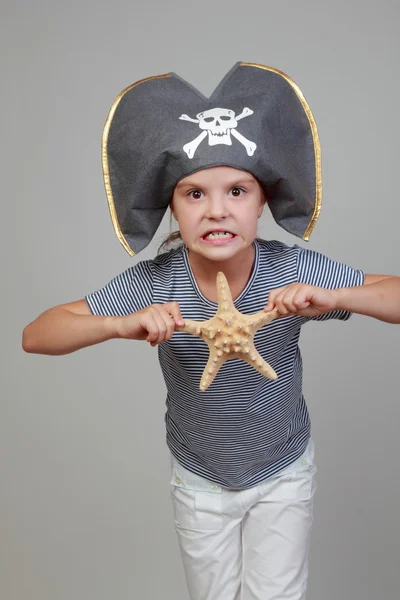 Girl in a pirate hat holding a starfish — Stock Photo, Image