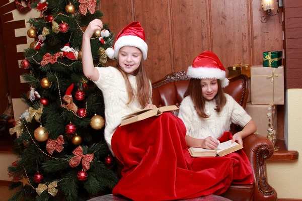 Girls wearing Santa hats holding books — Stock Photo, Image