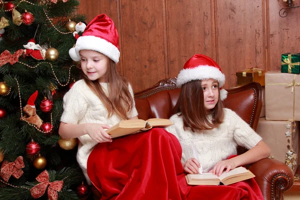 女孩子们穿着圣诞老人的帽子，拿着书 — 图库照片