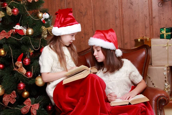 Flickor som bär santa hattar hålla böcker — Stockfoto