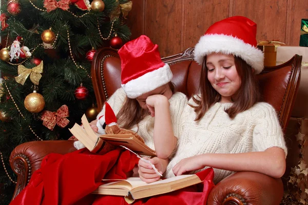 Girls wearing Santa hats holding books — Stock Photo, Image