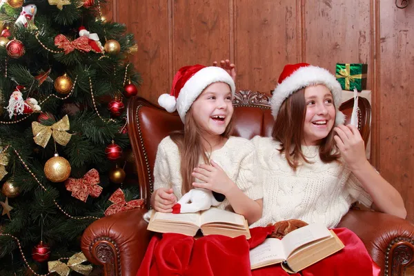 Girls wearing Santa hats holding books — Stock Photo, Image