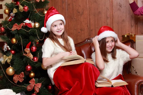 Mädchen mit Weihnachtsmützen halten Bücher in der Hand — Stockfoto