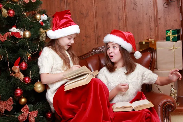 Girls wearing Santa hats holding books — Stock Photo, Image