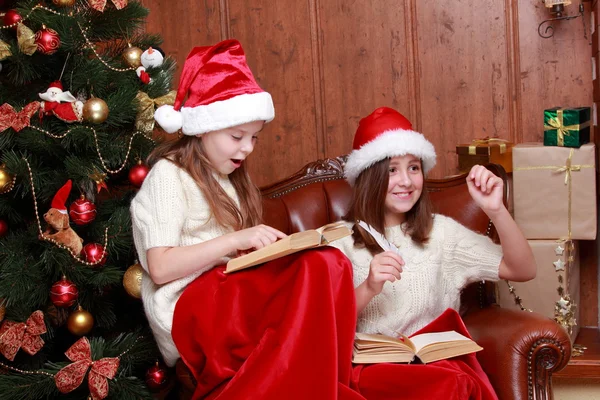 Ragazze che indossano cappelli di Babbo Natale in possesso di libri — Foto Stock