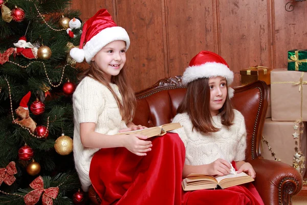 女孩子们穿着圣诞老人的帽子，拿着书 — 图库照片