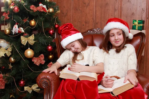 Girls wearing Santa hats holding books — Stock Photo, Image