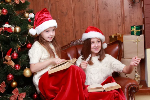 Girls wearing Santa hats holding books — Stock Photo, Image