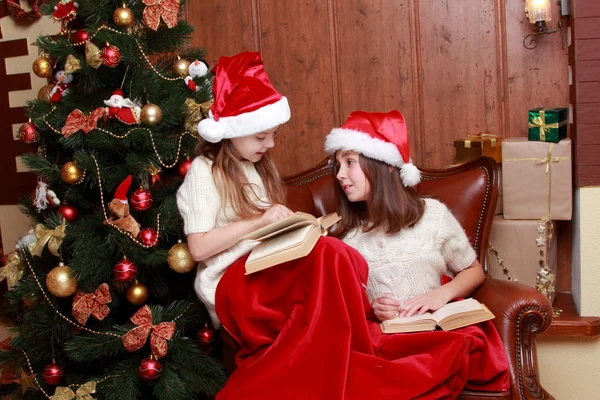 Girls wearing Santa hats holding books — Stock Photo, Image
