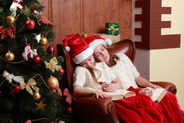 Girls wearing Santa hats holding books — Stock Photo, Image