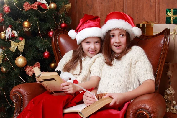 Girls wearing Santa hats holding books — Stock Photo, Image