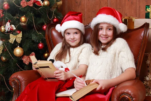 Ragazze che indossano cappelli di Babbo Natale in possesso di libri — Foto Stock