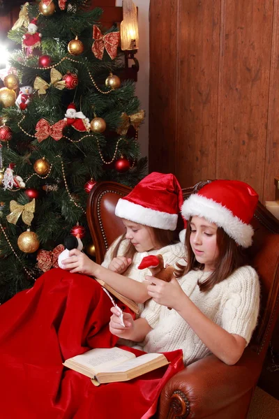 Girls wearing Santa hats holding books — Stock Photo, Image