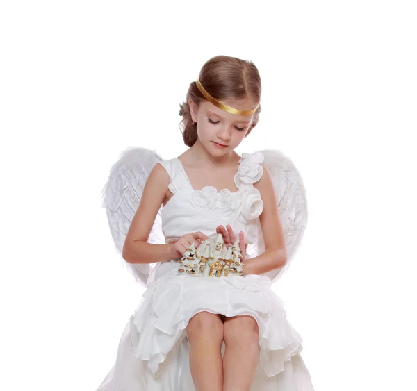 Pequeno anjo com casa minúscula de brinquedo Fotografias De Stock Royalty-Free