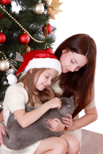 Matka a dcera hospodářství kočka přes vánoční stromeček — Stock fotografie