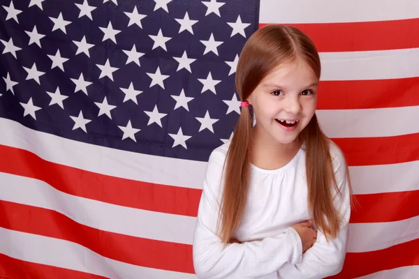 Menina no fundo de uma grande bandeira americana — Fotografia de Stock