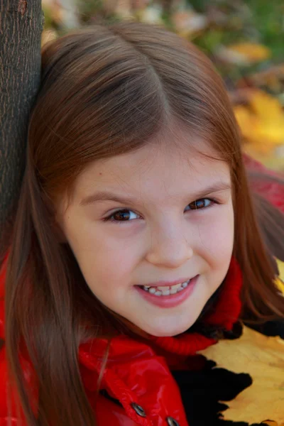 Girl playing with fallen leaves — Stock Photo, Image