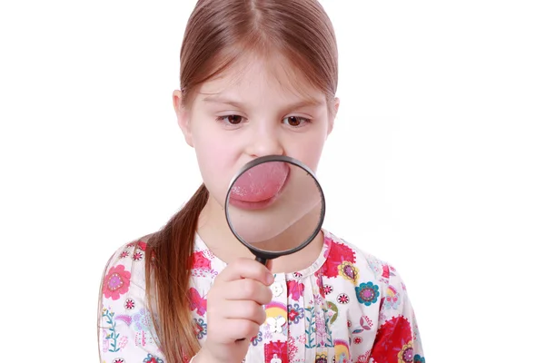 Girl show tongue through a magnifying glass — Stock Photo, Image