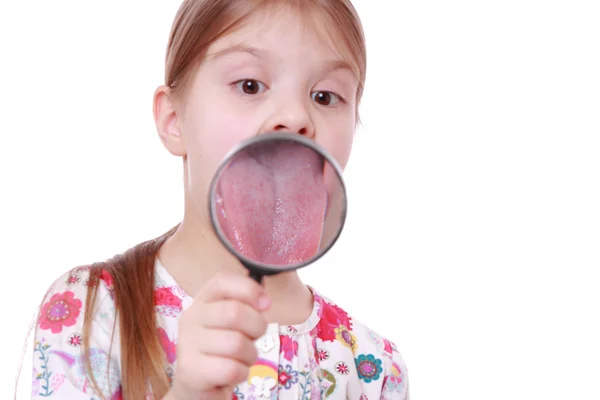 Девушка показывает язык через лупу — стоковое фото