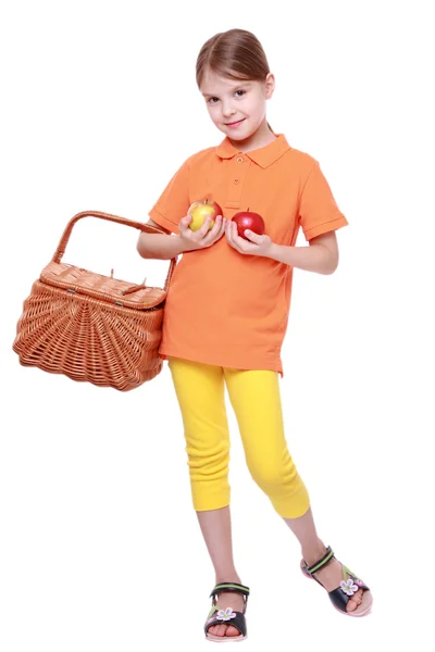 Flicka med äpplen och korg — Stockfoto