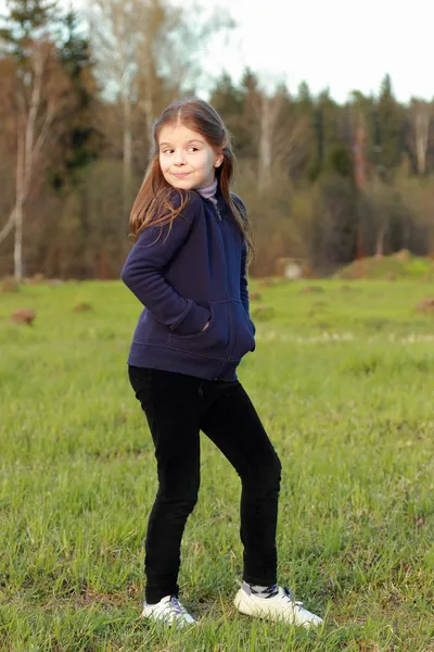 Маленькая девочка позирует на зеленой траве — стоковое фото