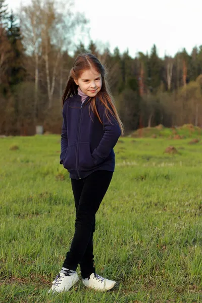 Petite fille posant sur l'herbe verte — Photo