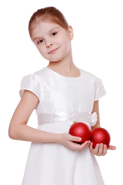 Meisje in een witte jurk bedrijf twee rode kerstballen — Stockfoto