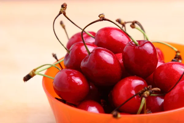 Sweet cherries in orange plastic bowl — Stock Photo, Image