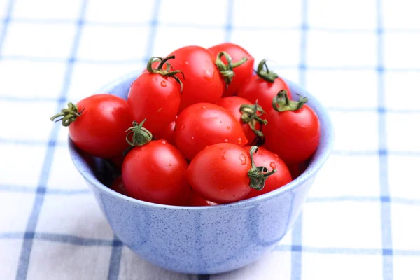 Cherry tomatoes in bowl on tablecloth — Stock Photo, Image