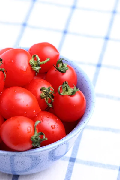 Tomates cereja em tigela na toalha de mesa — Fotografia de Stock