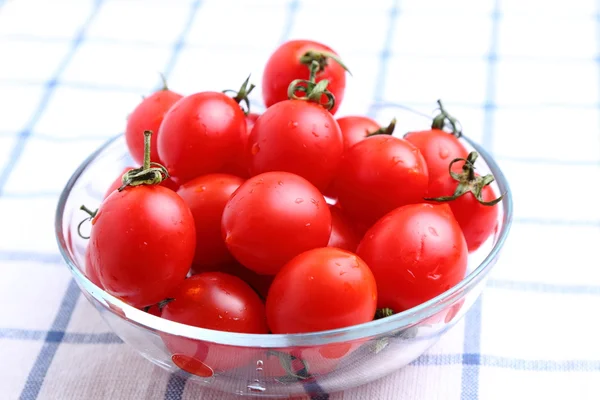 Tomates cereja em tigela de vidro na toalha de mesa — Fotografia de Stock