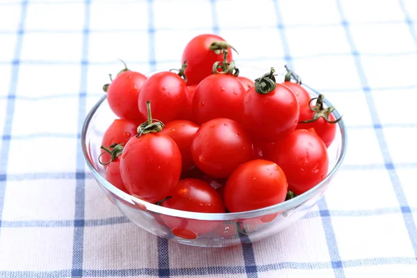 Tomates cereja em tigela de vidro na toalha de mesa — Fotografia de Stock