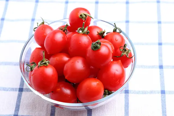 Cherry tomatoes in glass bowl on tablecloth — Stock Photo, Image