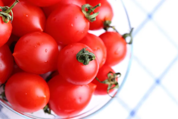 Tomates cereja em tigela de vidro na toalha de mesa — Fotografia de Stock
