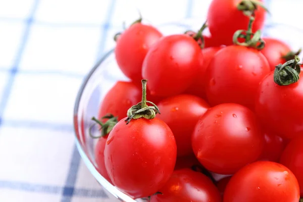 Tomates cereja em tigela de vidro na toalha de mesa — Fotografia de Stock