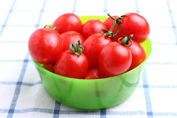 Cherry tomatoes in bowl on tablecloth — Stock Photo, Image