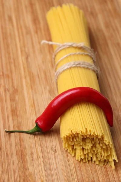 Uncooked pasta and chili peppers — Stock Photo, Image
