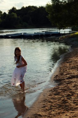 su üzerinde çıplak ayakla çalışan beyaz elbiseli kız