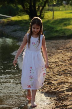 su üzerinde çıplak ayakla çalışan beyaz elbiseli kız