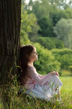 güzel bir yaz gününde ormanda yeşil çimenlerin üzerinde küçük bir kız