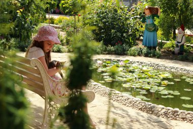 sevimli küçük kız parkta bankta oturmuş