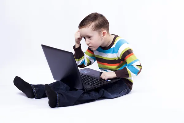 Ragazzo con un computer portatileRagazzo pensa guardando laptop — Foto Stock