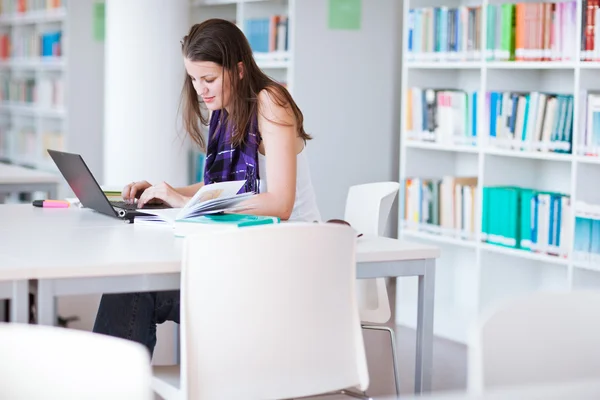 Bardzo kobiece kolegium student studia w bibliotece uniwersyteckiej — Zdjęcie stockowe