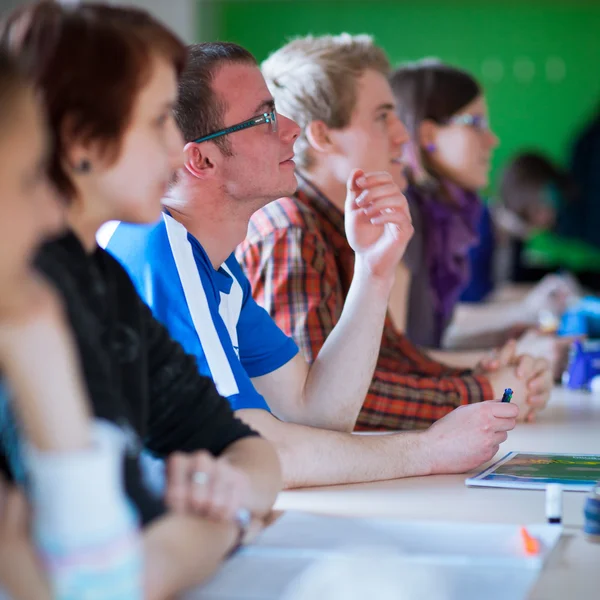 Jonge, knappe college student zitten in een klaslokaal vol met s — Stockfoto