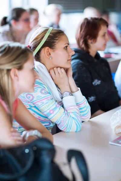 Joven, bonita estudiante universitaria sentada en un aula llena —  Fotos de Stock